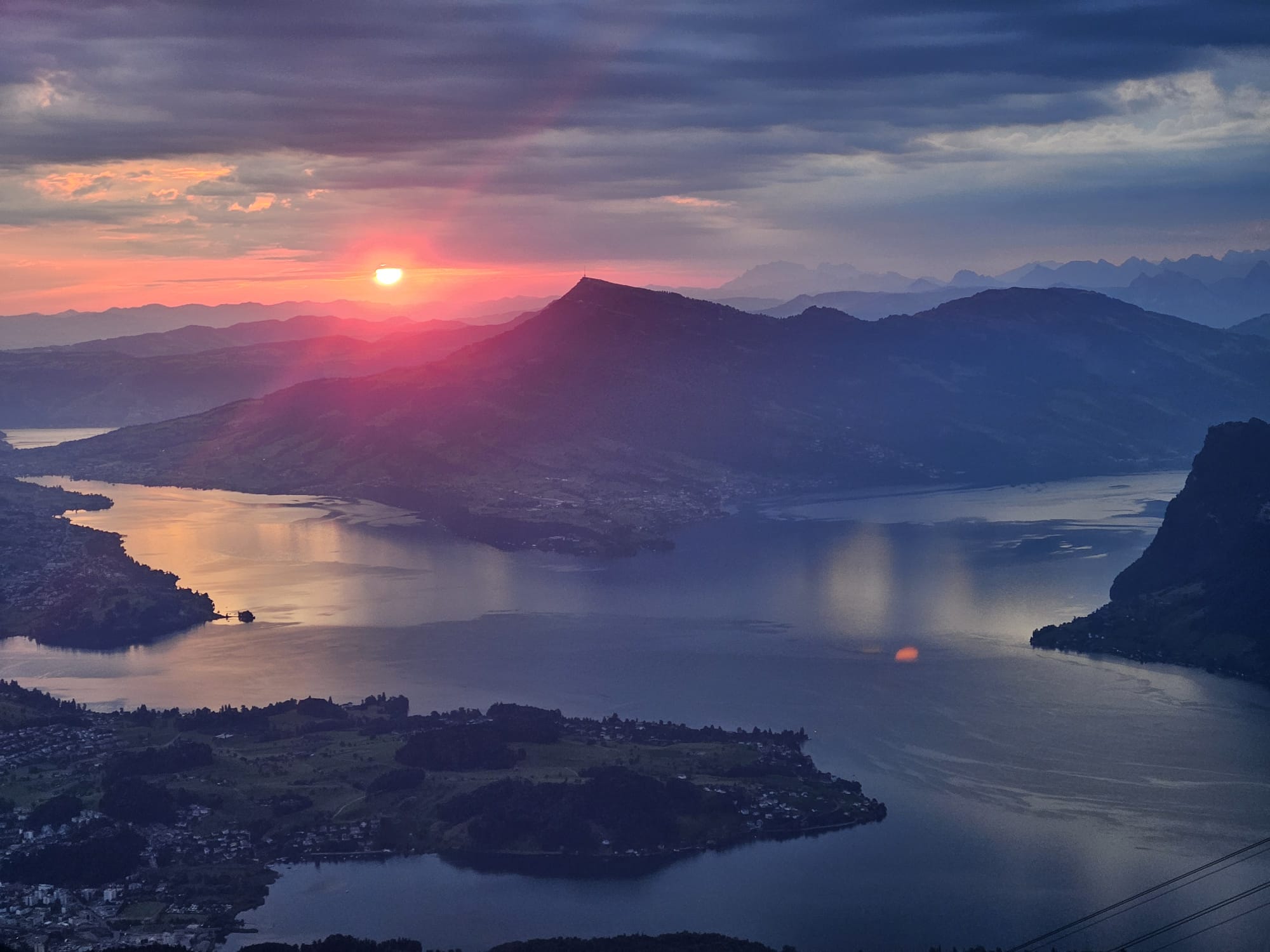 Sunrise over Lake Lucerne seen from Klimsenhorn, the water glowing pink and gold in the early light between dark mountain ridges