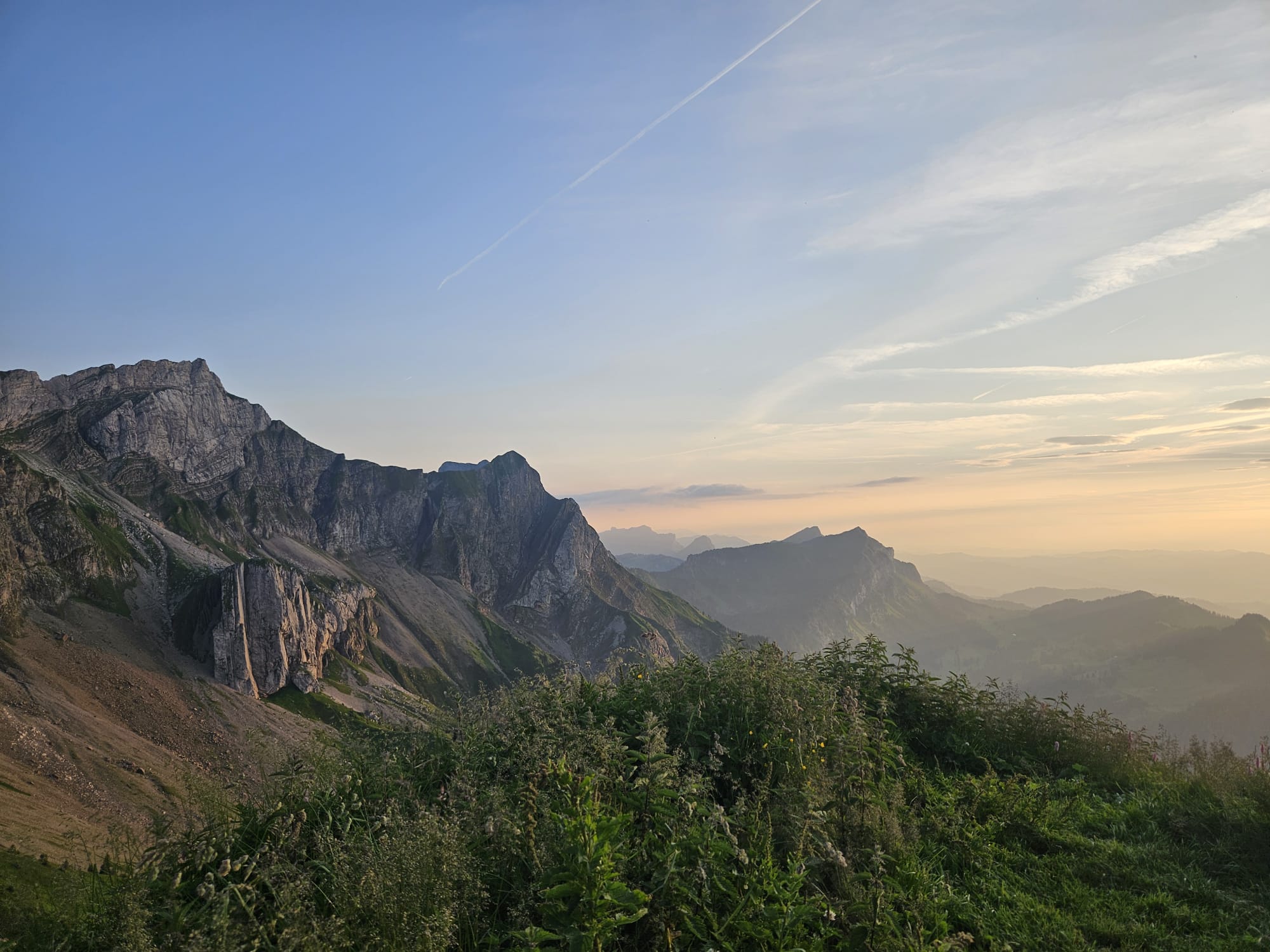 Sunset from the summit area of Klimsenhorn, warm evening light over the mountain ridges and the lake far below